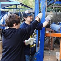 Two middle school boys pulling ch in a hands-on learning site. Two middle school boys pulling chains in a hands-on learning site.